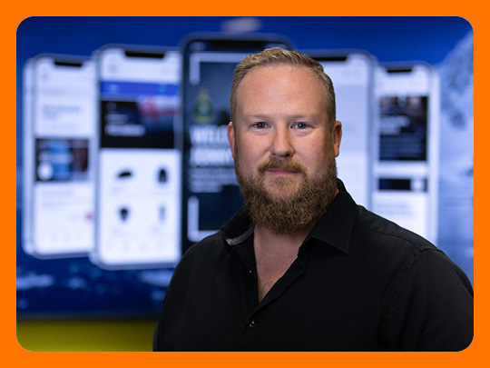 Image shows a member of the Government Digital and Data profession with blurred background of enlarged mobile phone screens