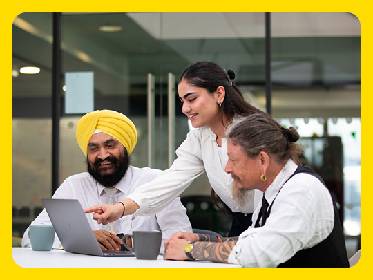 Image shows three people working round a laptop