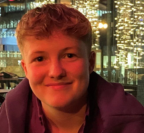 Decorative image: a Photo of Amber, a Level 3 Operational Delivery Apprentice In HMRC. They have short hair and are dressed casually and smiling at the camera.