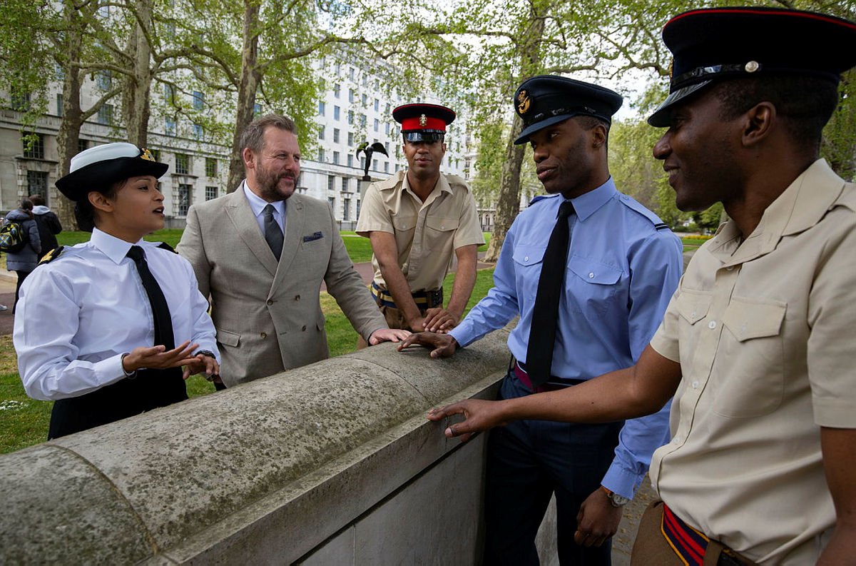 Photo of representatives from the armed forces, standing next to a grave.