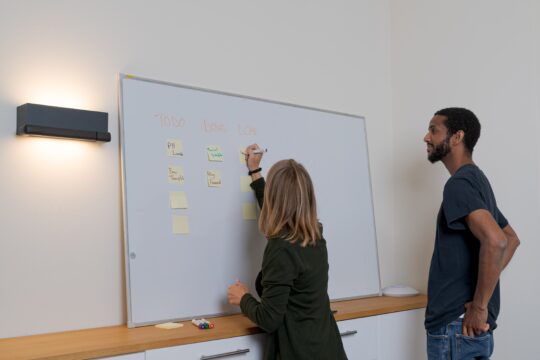 Two people collaboratively working on a whiteboard