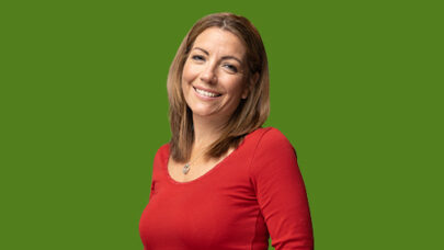DWP colleague smiling towards the camera. She is stood against a green background.