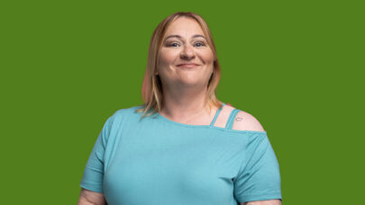 DWP colleague smiling straight to camera. She is stood against a green background.