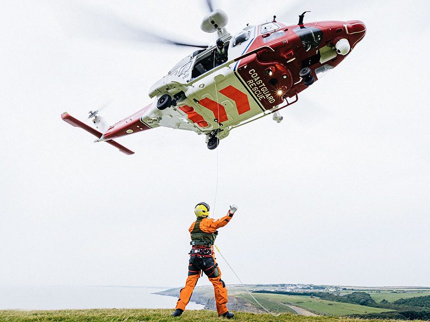 A photo of a helicopter being guided to a landing place by ground personnel