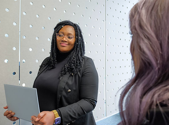 Woman walking through the office with a laptop