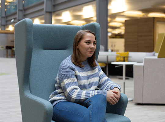 A photo of Eve, sitting In a large arm Chair in the office.