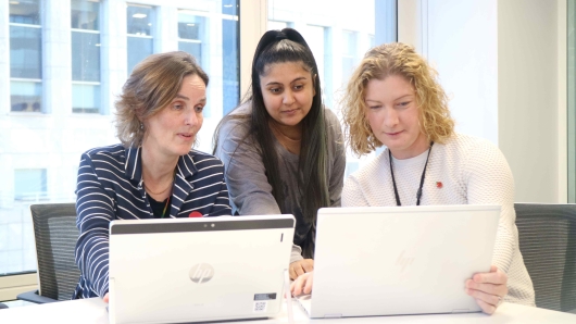 Three graduates working together on laptops