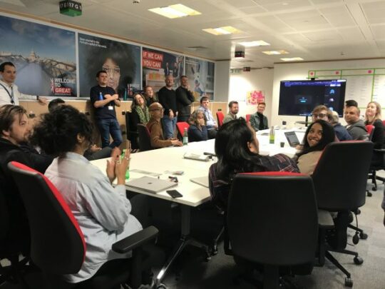 Decorative image: A large group of colleagues around a table having a lively discussion