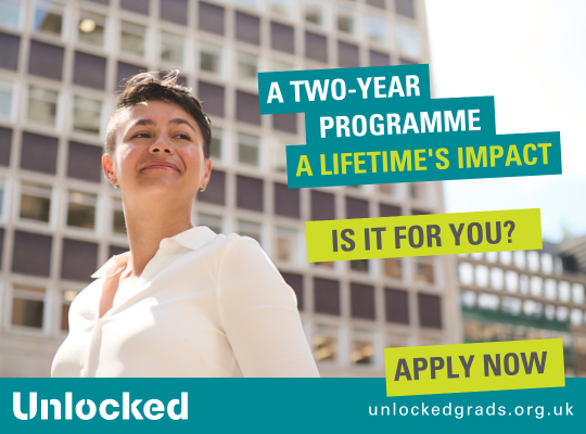 A graduate stands proudly in front of a building. The Unlocked graduates banner says 'apply now' with the tag line: