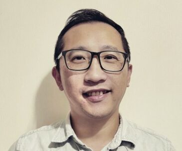 Headshot of HMRC employee, James, in front of a cream wall.