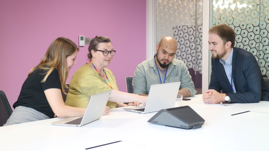 A group of CMA employees in a bright meeting room, having a discussion.