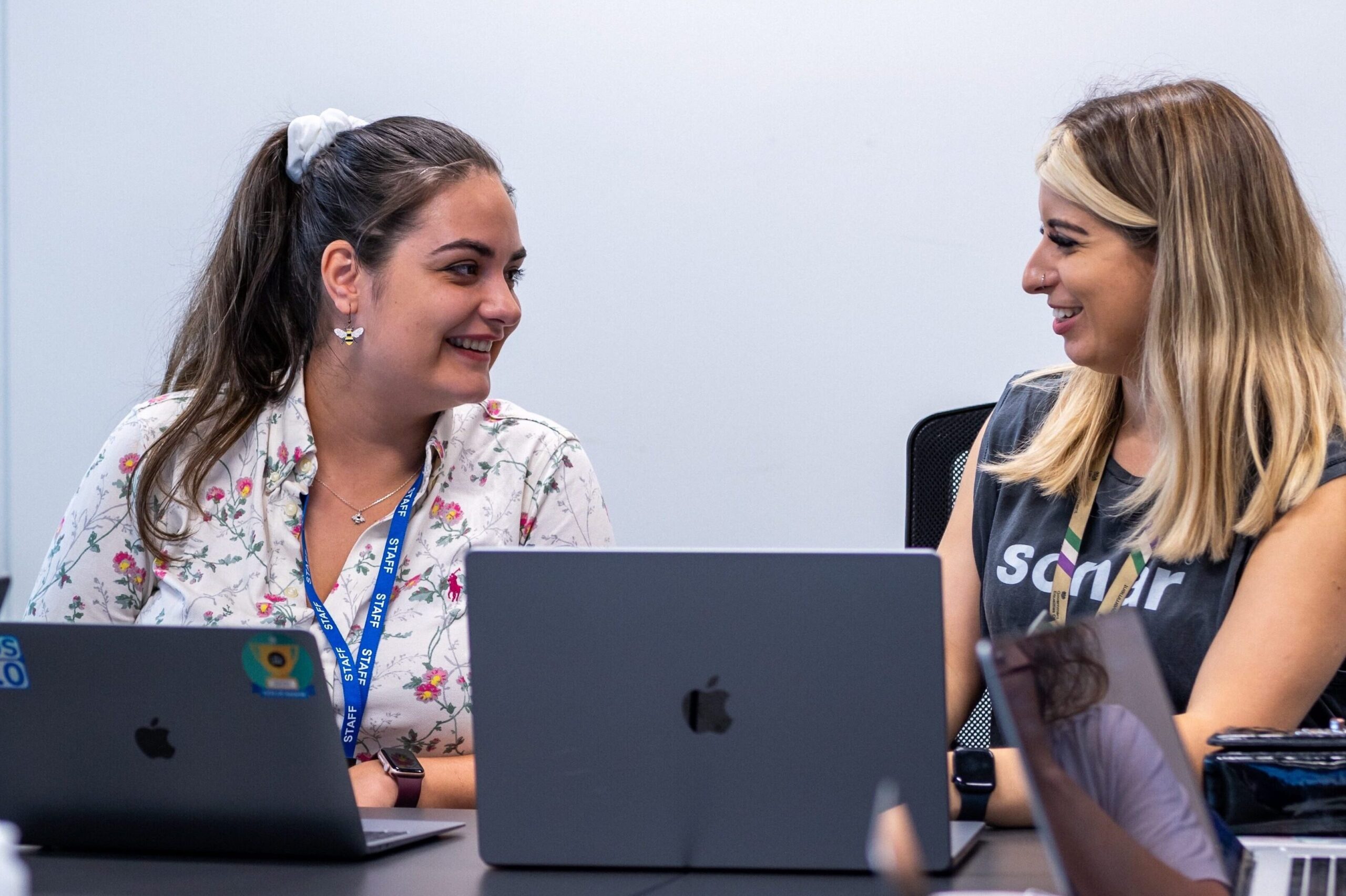 Decorative image: Two colleagues discuss work over a laptop