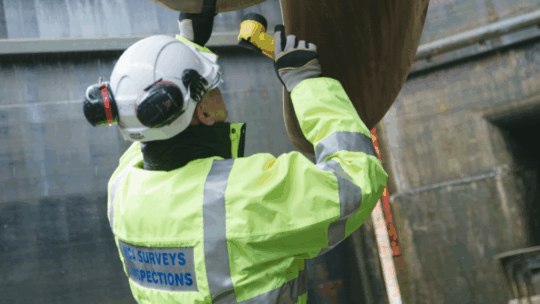 Marine surveyor, wearing safety clothing and inspecting a piece of machinery.