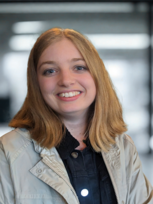 Katie Scott product manager is smiling  directly at the camera, while wearing a light coloured jacket and dark shirt.