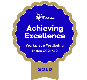 Infographic showing the Mind charity logo in a rosette. The rosette also contains the words "Achieving excellence, Workplace wellbeing index 2021/22"