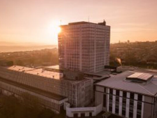 An imposing skyscraper, with a honeycomb of windows, pictured at sunset.
