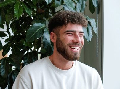 Man sat smiling looking out a window in a relaxed office environment