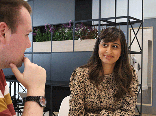 Two colleagues sat at a table having a conversation