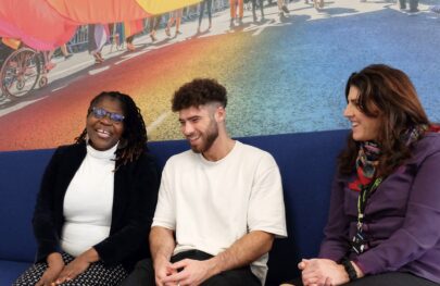 Three colleagues sat on a sofa laughing together