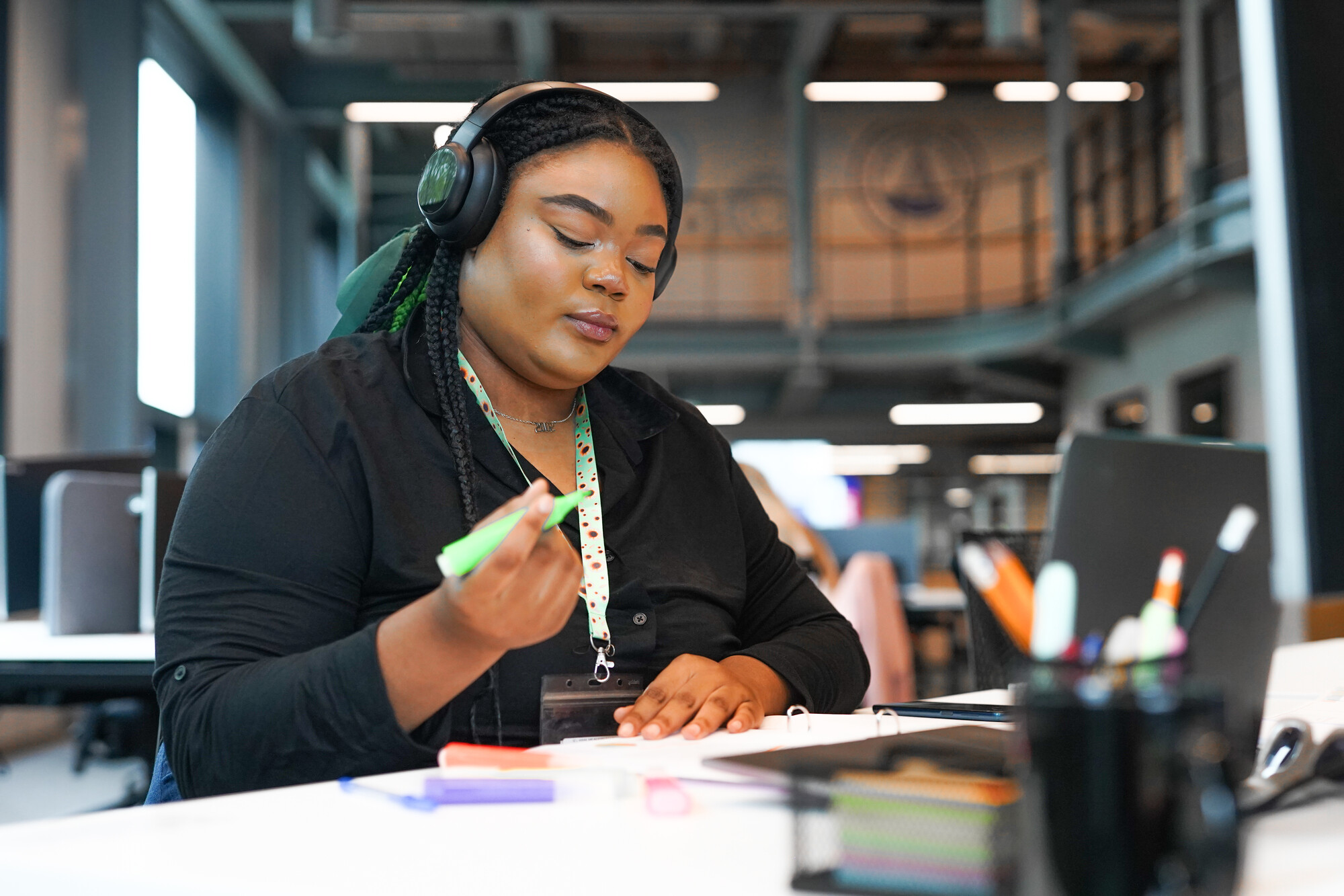 A woman with a less visible disability working on a laptop. She is wearing a sunflower lanyard.