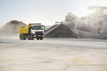 A large tipper truck driving through an industrial construction site.