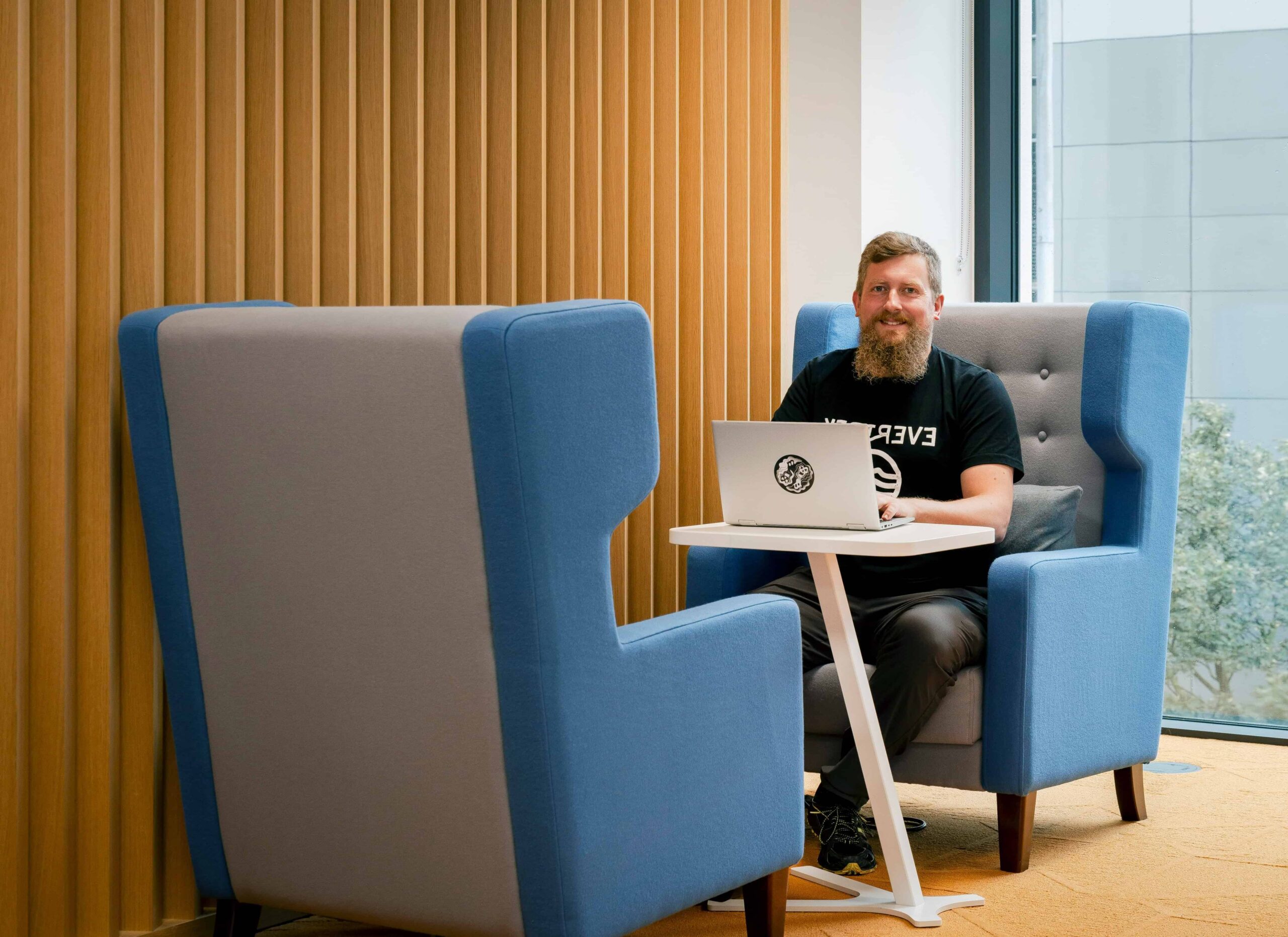 man sat at a desk with a laptop smiling