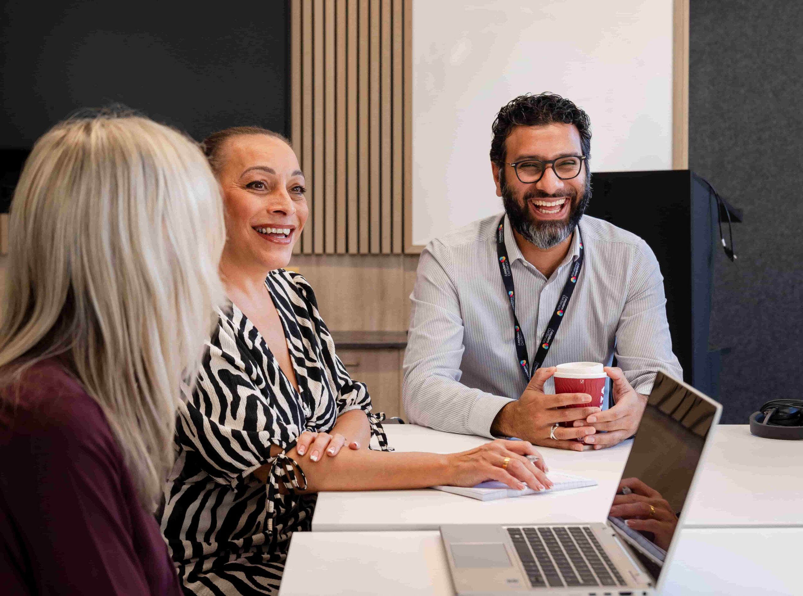 colleagues sat at a desk smiling