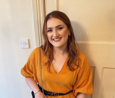 Rachel smiling at the camera wearing an orange dress