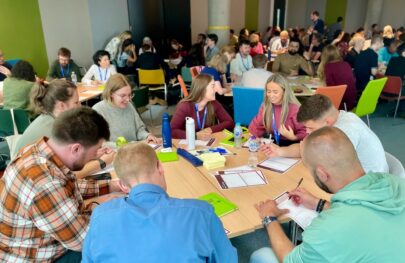 A group of HMRC employees sitting round a large table taking part in an interactive activity in a conference setting.