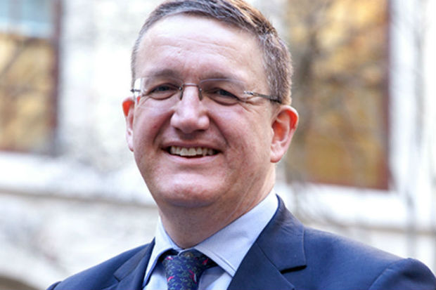 Photo of Rupert McNeil, he is wearing a suit and tie in a navy blue colour, and is smiling at the camera.