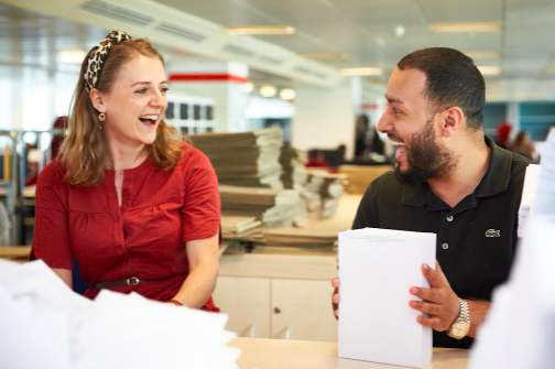 Two civil Servants laughing together in a bright office