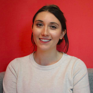 A photo of Georgina Allsopp. She is in front of a red background and has her dark hair tied back.
