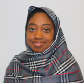 A photo of Amina Mahammad. She is wearing a grey and red tartan hijab.