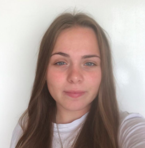 Photo of Shauna Compton. She has long dark blonde hair and is wearing a white tshirt