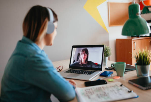 A woman at her desk at home, chatting to a female colleague on a video call