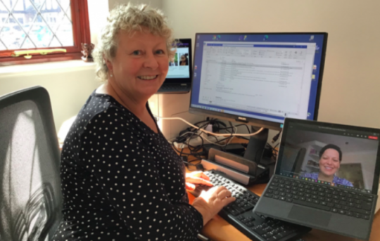Decorative image: Photo of Tina Walker and Deanna Caszo, HM Revenue and Customs. Tina is at her desk, and Deanna is on a zoom call, on a laptop. Both are smiling at the camera.