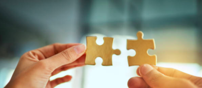 Two hands, each holding a puzzle piece.