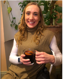 A photo of Anna - Senior User Researcher. She is dressed casually and holding a mug of coffee.