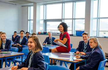 A photo of a classroom, with students and a teacher laughing together