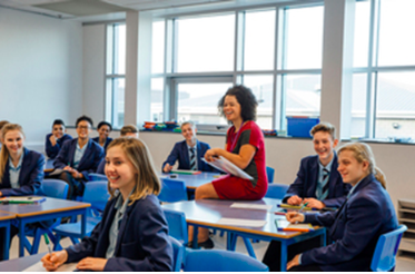 A photo of a classroom, with students and a teacher laughing together