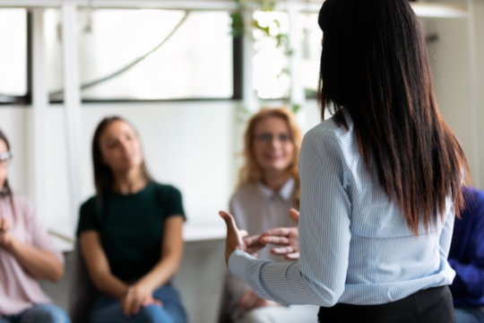 A woman presenting to some colleagues, her back is to the camera.