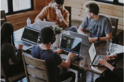 A group of four (4) people working on laptops, around a table