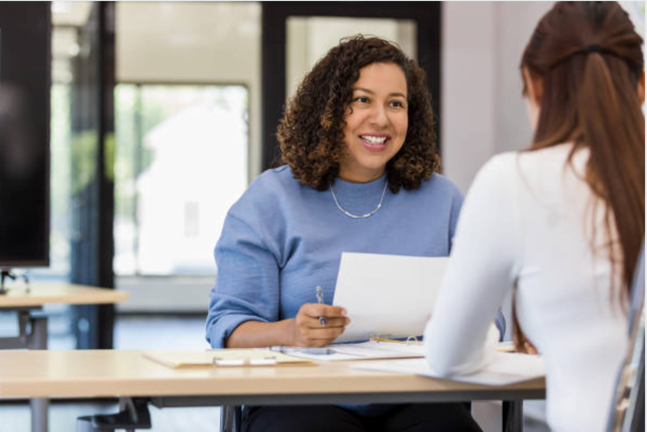 A woman interviewing another woman. The woman being interviewed has her back to the camera.