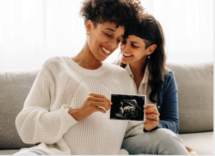 Two women holding a scan photo of their baby