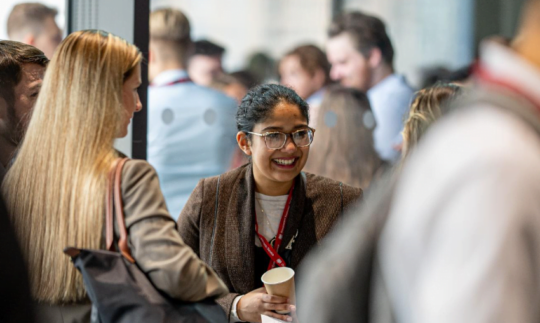 A group of colleagues at an event, drinking coffee and chatting animatedly