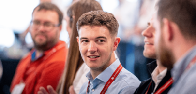 Four colleagues talking to each other at an event, they are all sitting, in a crowded room