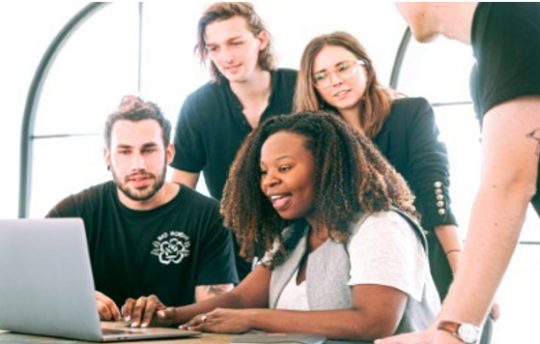Decorative image: five colleagues all looking at a laptop together