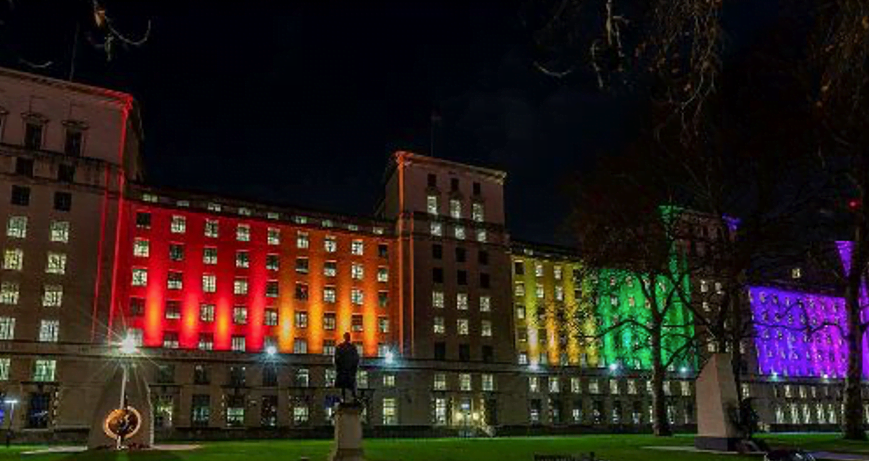 Decorative image: a building at night, lit up in rainbow colours