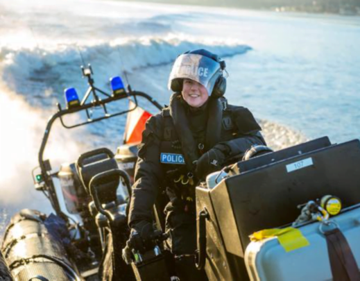 Decorative image: a woman in a police uniform, piloting a small boat.