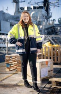 MoD - Decorative image: A photo of Tanya, a former moD Apprentice. She is standing dockside, next to a large military ship